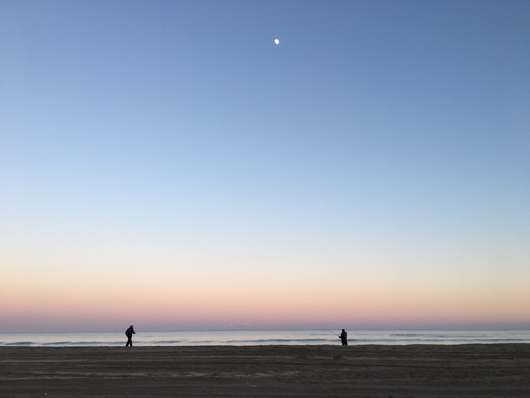 九十九里浜の夕陽 月と釣り人とランニングする人