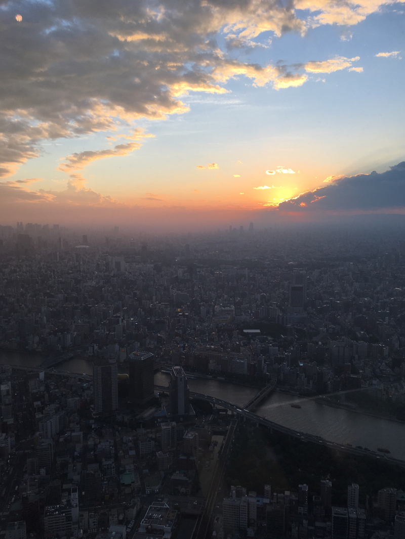 東京スカイツリーから雲の合間に落ちていく夕日を眺める